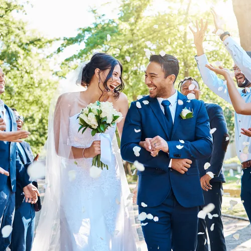 Wedding guests tossing petals at the couple